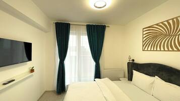 Ein Hotelzimmer mit einem Bett, einem an der Wand montierten Fernseher, einem Heizkörper und einer Wanddekoration.
