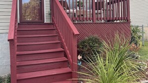 Une maison à deux étages avec un escalier rouge menant à un porche.