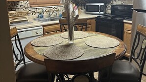 Une cuisine avec des meubles en bois, un four à micro-ondes, une cuisinière et une table à manger avec des sets de table.