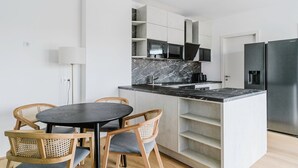 A modern kitchen with white cabinetry, a marble countertop, and a built-in refrigerator. - Blueground | Donaustadt, furnished & ready (Vienna)