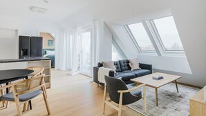 A modern apartment with a kitchen, dining area, and living room. It features a large skylight, a sofa, and a dining table. - Blueground | Donaustadt, furnished & ready (Vienna)