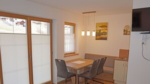 A compact living space with a dining area, kitchenette, and a sliding door leading to a balcony.