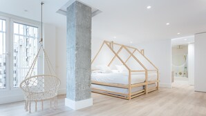 Ein modernes Schlafzimmer mit einem Holzbettgestell, einem Hängekorbsessel und einer Betonsäule.