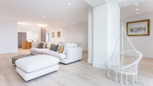Ein modernes Wohnzimmer mit einem weißen Sofa, einem Hängesessel und einem Bild an der Wand.
