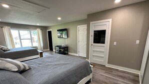 Un dormitorio con una cama grande, una cama más pequeña, un televisor y una puerta.