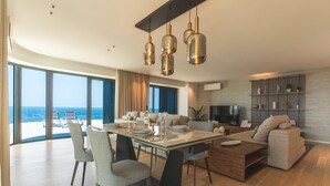 A modern living room with a dining area, large windows, and a view of the sea. - Majestic Penthouse View by Atlantic Holiday (Funchal)
