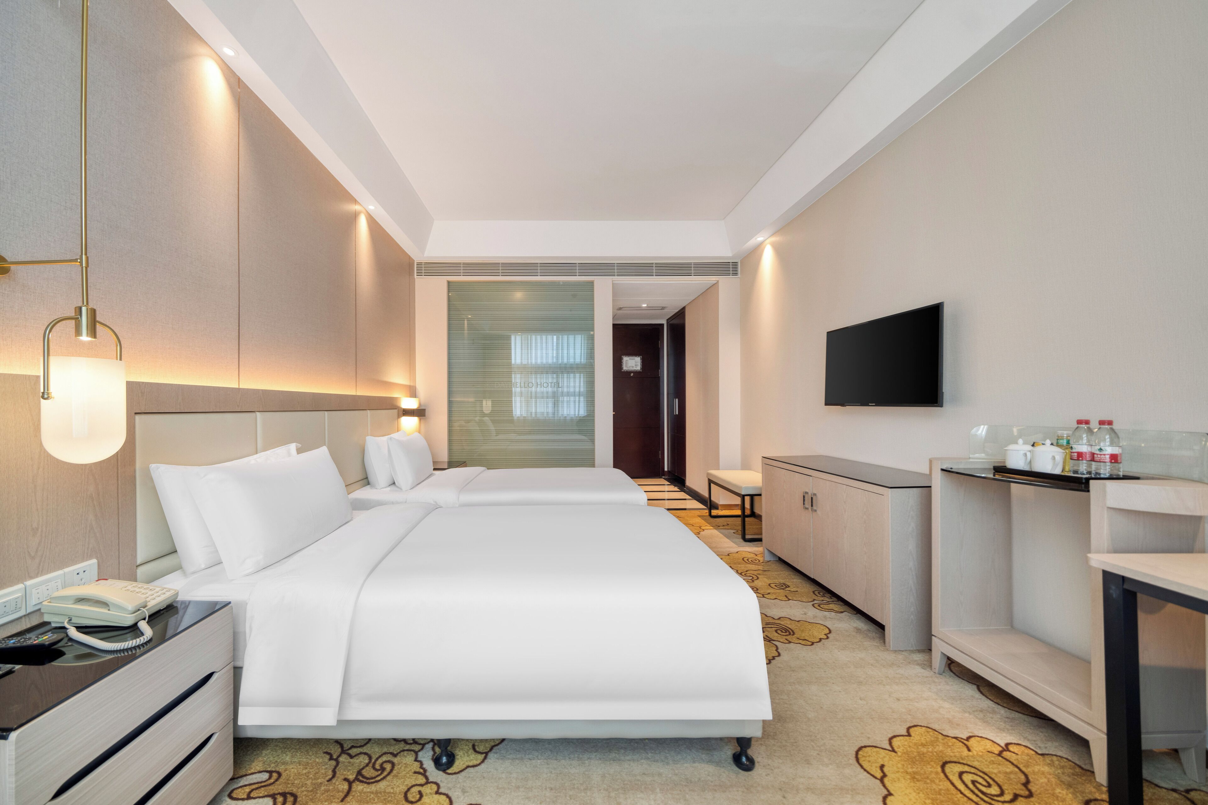 Habitación de hotel con dos camas, un escritorio, una silla, un televisor y un minibar.
