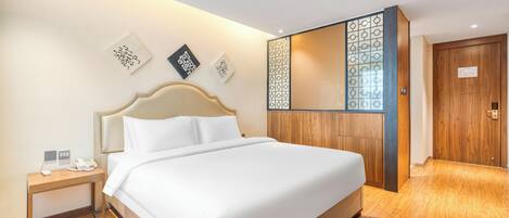 Habitación de hotel con una cama grande, una mesita de noche con teléfono y un armario de madera.