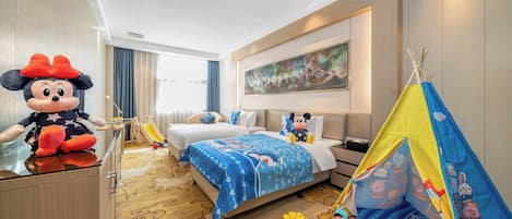 A hotel room with a Mickey Mouse plush toy, a bed with a blue Mickey-themed bedspread, a play tent, and a large abstract painting on the wall.