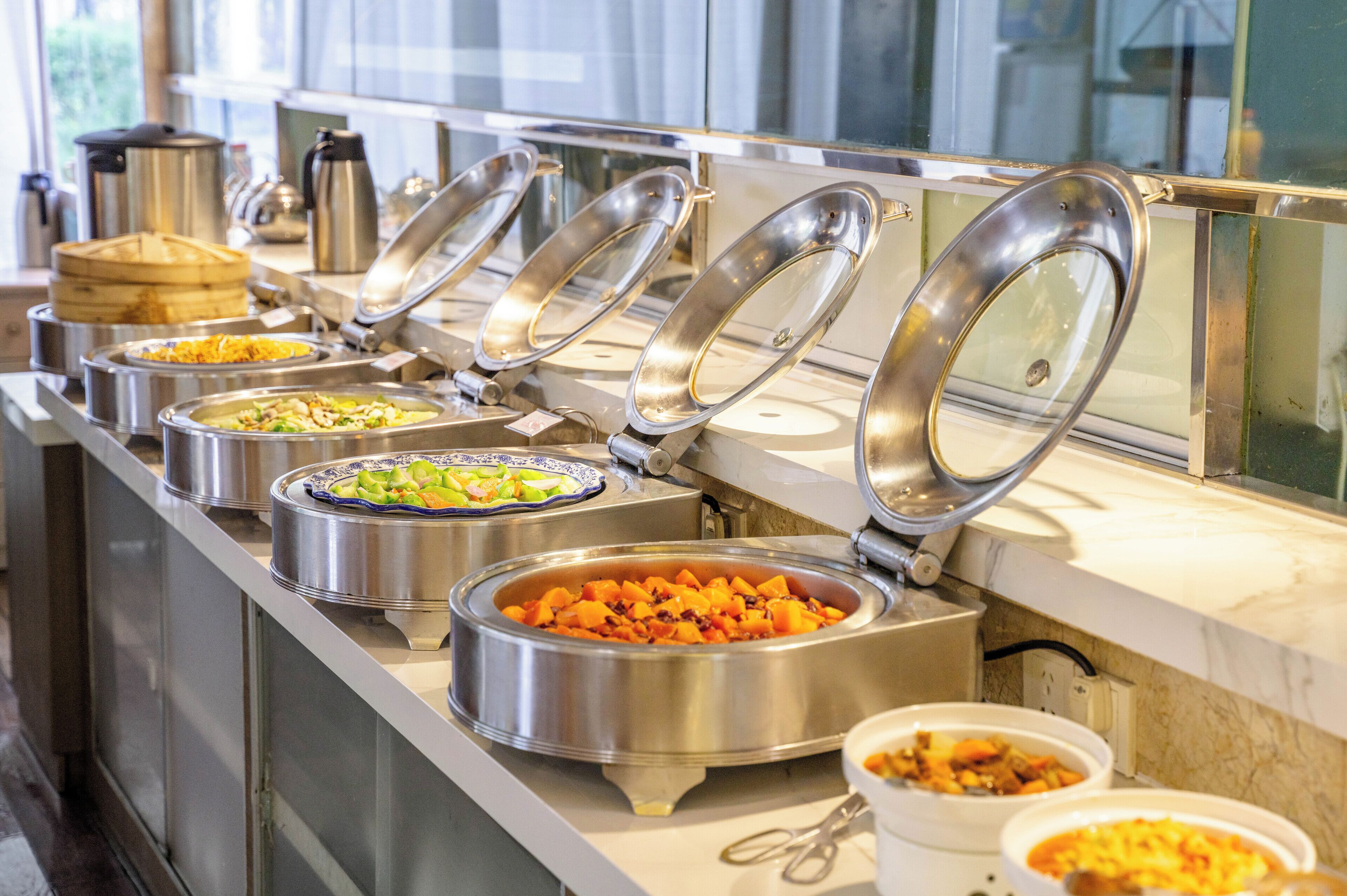 A buffet line with various food containers and utensils.