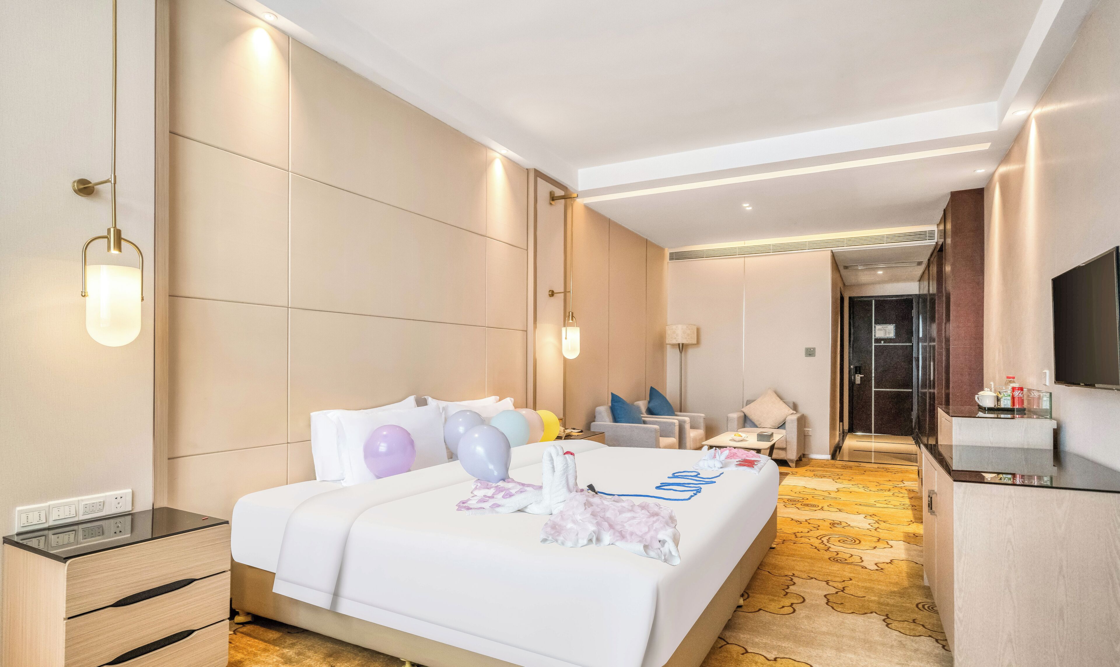A modern hotel room with a large bed, bedside tables, a desk, and a television.