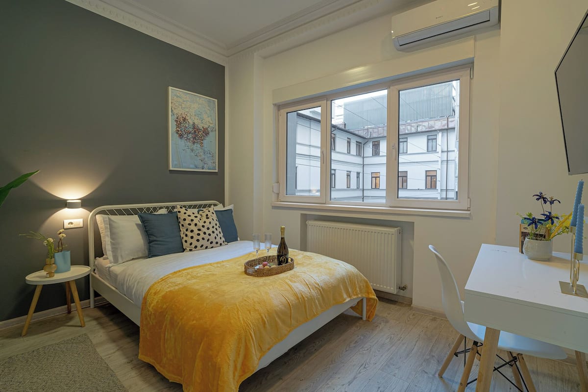 Une chambre à coucher avec un lit, une table de chevet, une fenêtre et un bureau.