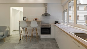 A modern kitchen with a built-in oven, a stainless steel range hood, and a window overlooking the city. - Central 4BR Flat - 2 Units Combined with Balconies, Near Cismigiu, 2 Kitchens & 2 Baths (Bucharest)