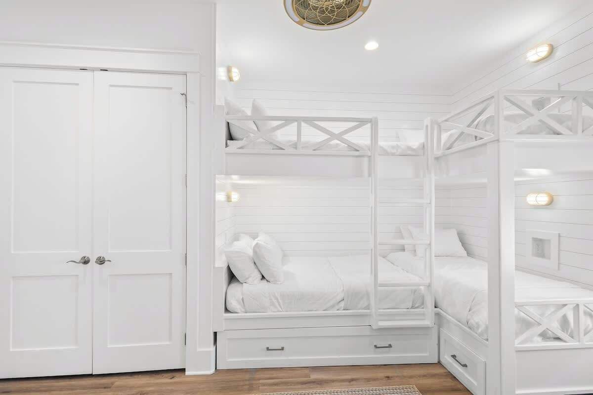 A white room with a bunk bed, a wardrobe, and a ceiling light fixture.