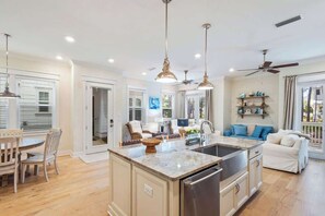 A spacious kitchen with a central island, pendant lighting, and a ceiling fan.