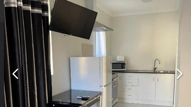 A compact kitchen with a refrigerator, microwave, and sink. - Dash motel (Papakura)