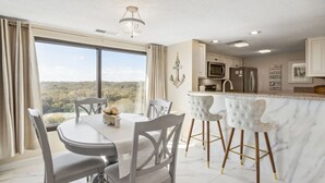 Una cocina moderna con encimera de mármol, electrodomésticos de acero inoxidable y vistas al exterior.