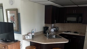 A compact kitchen with a microwave, toaster, and sink. There are two wooden stools and a wooden table. - Studio Apartment- Steps from the beach! (Deerfield Beach)