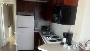 A compact kitchen with a refrigerator, stove, microwave, and a small sink.