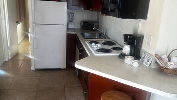 A compact kitchen with a refrigerator, stove, microwave, and a small sink.