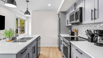 A modern kitchen with grey cabinets, a stainless steel sink, and a microwave.