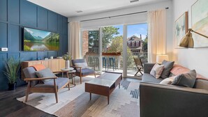 Un salon moderne doté d’un grand téléviseur, de sièges confortables, d’un balcon avec vue et d’un coin cuisine.