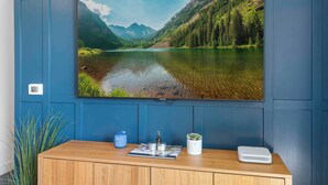 Un téléviseur à écran plat fixé à un mur bleu, diffusant une image d’un magnifique lac de montagne.