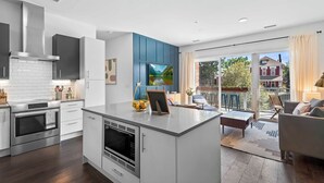 Une cuisine moderne dotée d’un îlot central, d’appareils électroménagers intégrés et d’une grande fenêtre donnant sur un balcon.