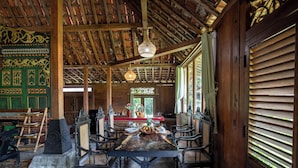 Un coin repas traditionnel, aménagé en bois, avec une grande table, des chaises et des luminaires suspendus.