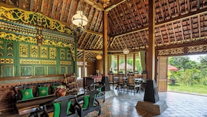 Un espace intérieur doté de poutres en bois au plafond, de murs ornés de motifs verts et d’un sol carrelé.