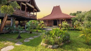 Une maison traditionnelle en bois, dotée d’un balcon, et un bâtiment séparé avec un toit en tuiles.
