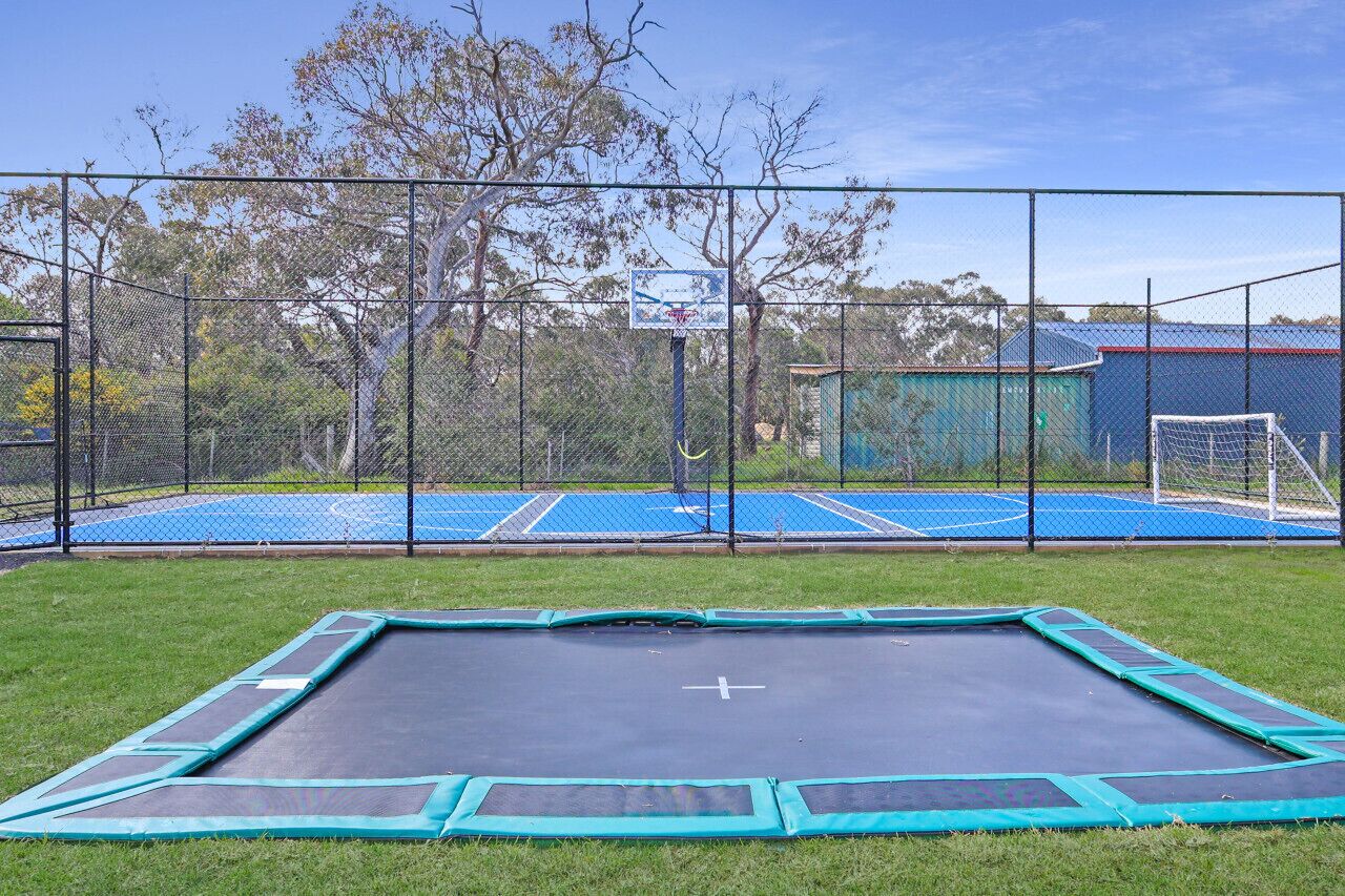 Un espacio al aire libre cercado con un trampolín y una cancha de baloncesto.