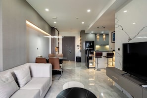 A modern living room with a sofa, dining area, kitchen, and a TV. - The Peak M8 Midtown (Ho Chi Minh City)