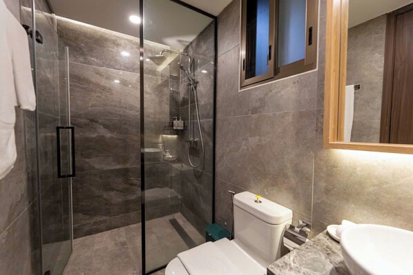 A modern bathroom with a glass-enclosed shower, a toilet, and a sink. - The Peak M8 Midtown (Ho Chi Minh City)