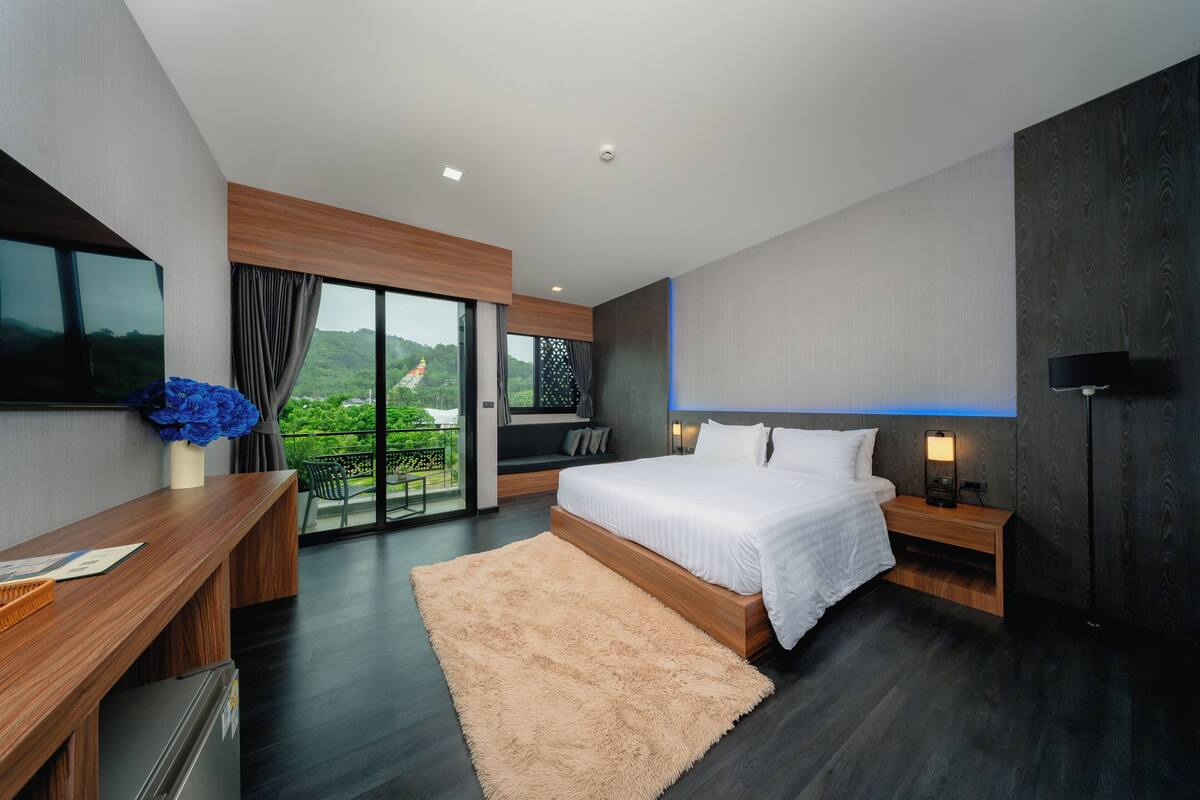 A modern bedroom with a large bed, a desk, and a TV.