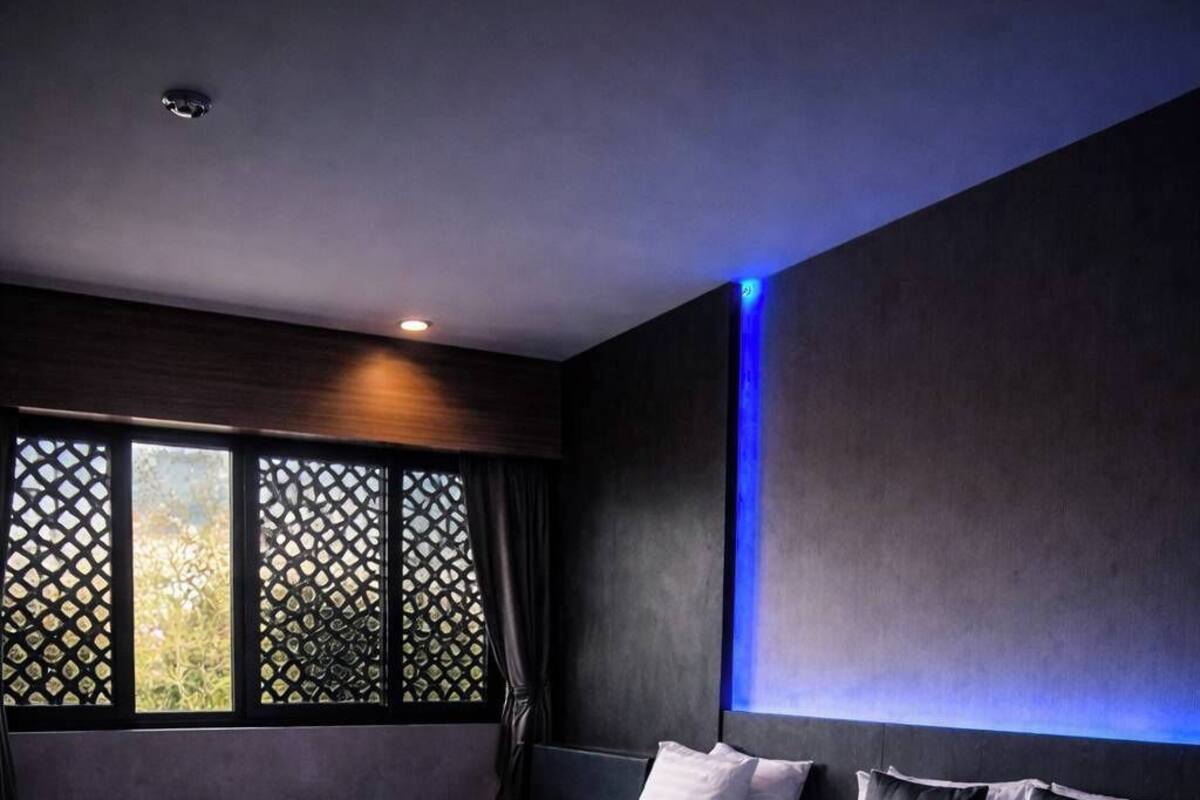 A modern bedroom with two beds, a large window with a view, and a blue accent wall.