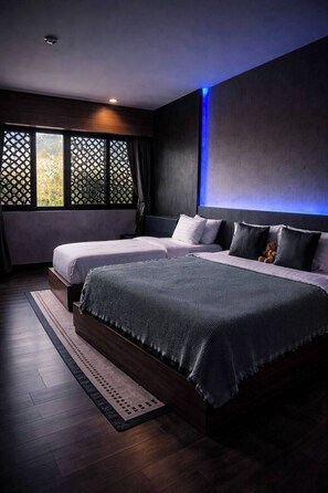 A modern bedroom with two beds, a large window with a view, and a blue accent wall. - Happy Hotel Ao Nang Krabi (Krabi)