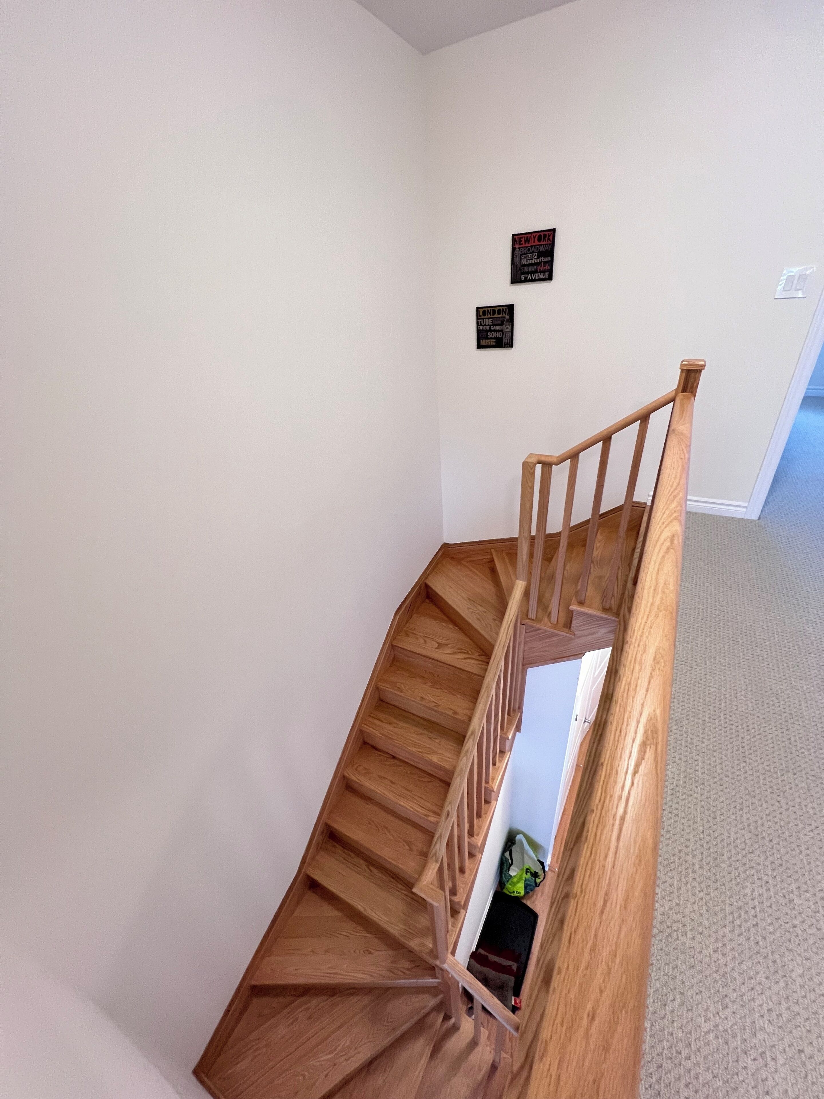 Eine Holztreppe mit Handlauf, einem Teppichbelag und zwei Schildern an der Wand.