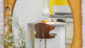 A kitchen with a white brick wall, a wooden bar stool, and a countertop with a glass and a small container. - Gapyeong Nd209 spa Pension (Gapyeong)