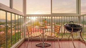 Ein Balkon mit Tisch, Stühlen, einer Weinflasche und einem Grill.