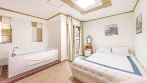 Une chambre d’hôtel avec un grand lit, une baignoire, un miroir et un tableau au mur.