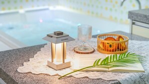 A cozy reading area with a lit lantern, a glass of water, and a basket of oranges on a table with a lace doily. - Gapyeong Nd209 spa Pension (Gapyeong)