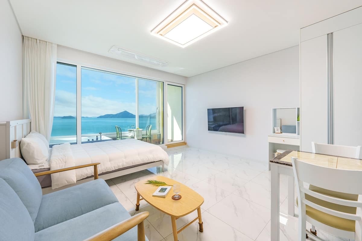 Ett modernt hotellrum med en stor säng, en soffa, ett matbord och en TV.