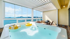 A hot tub with two yellow inflatable rings, a table with chairs, and a grill. - Yeosu Stay Raonpine Spa Pension (Yeosu)