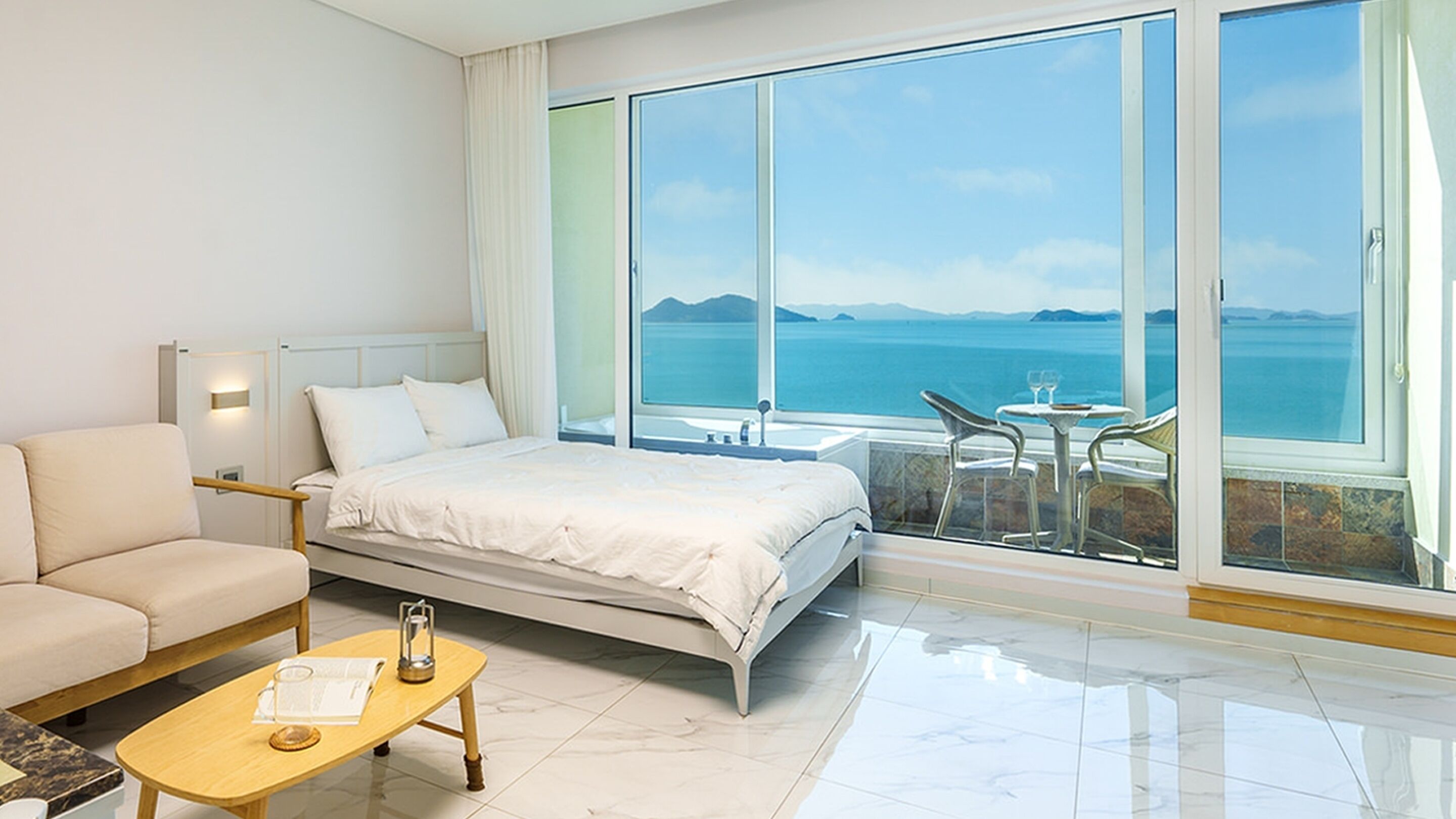 Habitación de hotel con una cama, un sofá, una mesita y vista al mar.