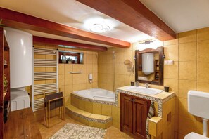 Une salle de bain avec une baignoire, deux lavabos, des toilettes, un porte-serviettes et une douche.