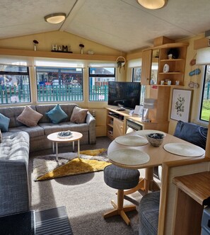 Relax in a cozy living area with a comfortable sofa, round table, and TV, offering stunning views of the outside.