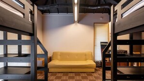 Une chambre avec un lit superposé, un canapé et un tapis à motifs.