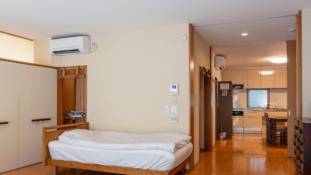Une chambre à coucher avec un lit en bois, une armoire et un appareil de climatisation.