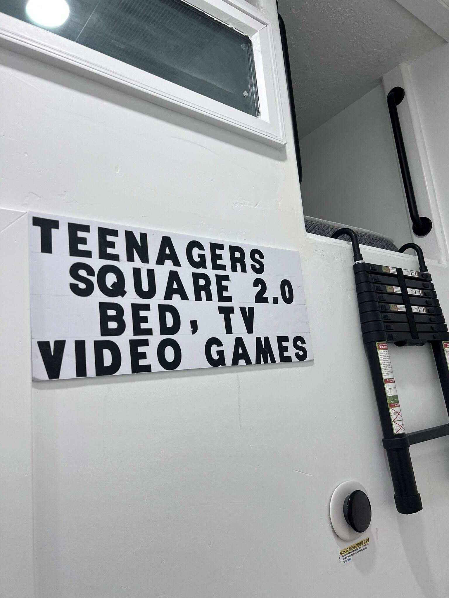 Schild, das einen Raum für Jugendliche mit einem Bett, einem Fernseher und Videospielen kennzeichnet.